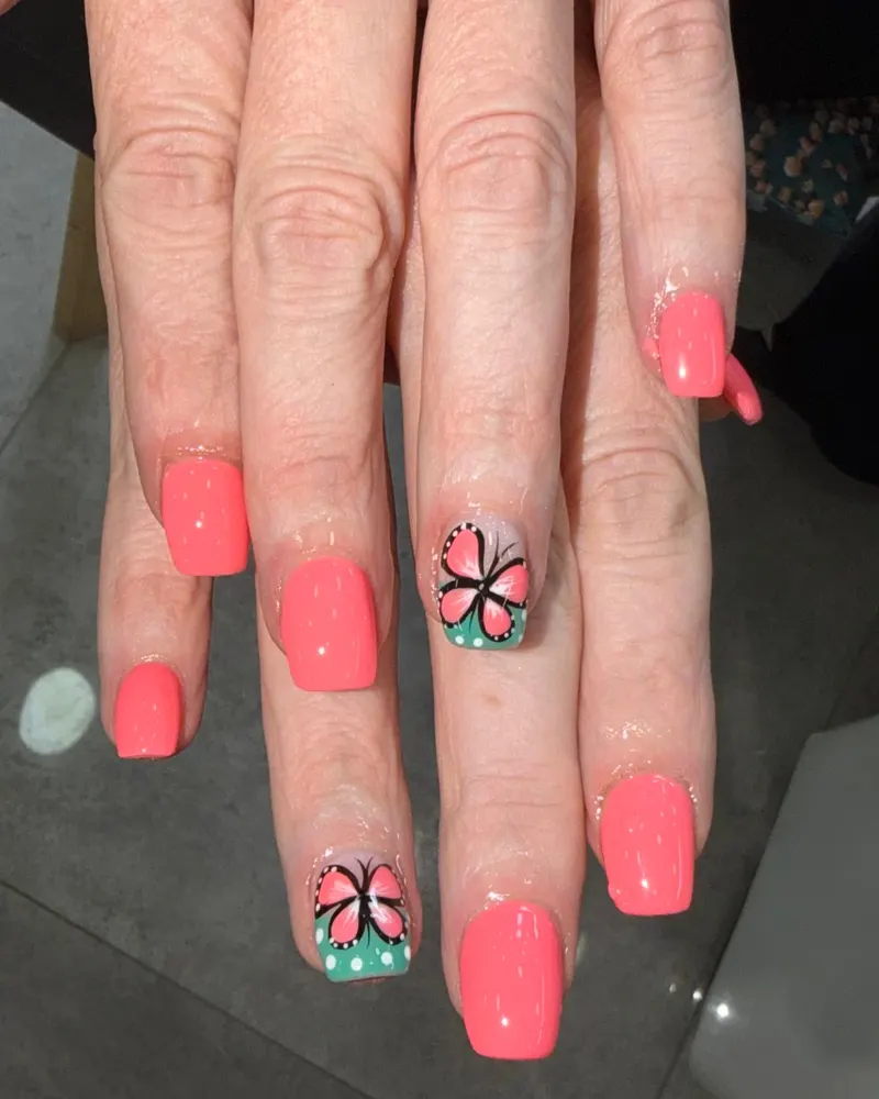 Coral nails with a butterfly accent